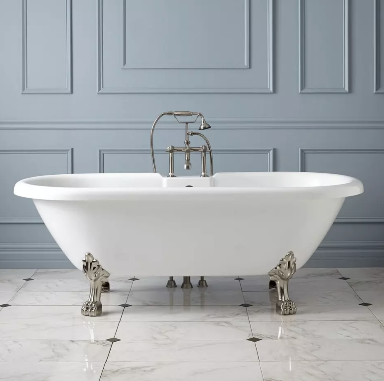 White clawfoot bathtub with polished silver feet on elegant marble tile in a luxury bathroom remodel