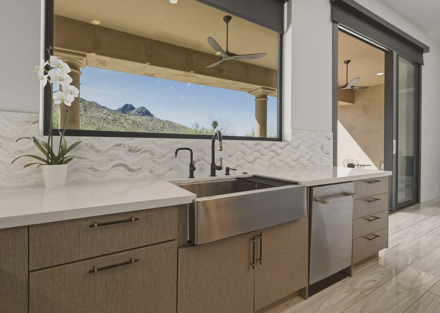 Kitchen with medium tone wood cabinets, large stainless steel sink, oil rubbed bronze faucet and soap dispenser, secondary faucet, and stainless steel dishwasher.